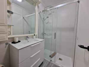 a white bathroom with a shower and a sink at Elegante Apartamento con Vistas al Mar in Suances