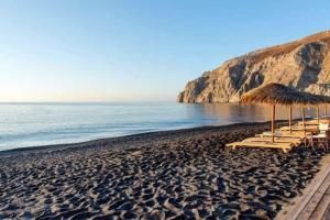 a beach with chairs and umbrellas and the ocean at Rodi Apartments 1 in Kamari