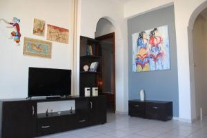 a living room with a flat screen tv on a entertainment center at Rodi Apartments 1 in Kamari +25 photos