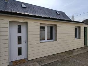 een garage met twee ramen en een witte deur bij Le Hutteau in Vaudricourt