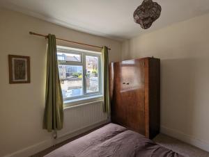 1 dormitorio con cama y ventana en 5 bed terraced family home Bristol + parking, en Bristol