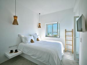 a white bedroom with a bed and a window at CasaZu in Naousa