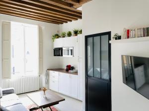 eine Küche mit weißen Schränken und einem schwarzen Kühlschrank in der Unterkunft Studio rénové et tres fonctionnel, Marly-le-Roi in Marly-le-Roi