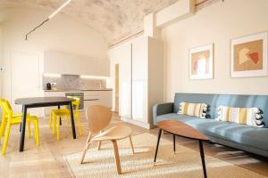 - un salon avec un canapé bleu et des fauteuils jaunes dans l'établissement Casa Aldrovandi: Elegante e in Centro Storico, à Bologne