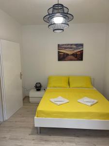 a bedroom with a bed with yellow sheets and a chandelier at Apartments Lovro in Lovran