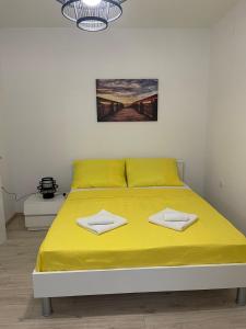 a bed with yellow sheets and towels on it at Apartments Lovro in Lovran