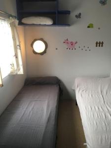 a small bedroom with two beds and a window at Mobil Home + dépendance dans jolie parc privé in Sérignan