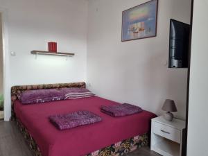 sypialnia z łóżkiem z fioletową pościelą i telewizorem w obiekcie Kristina w mieście Vrbnik
