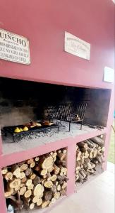 a barbecue with two chairs and a pile of fire wood at AMOR & MIEL in General Alvear