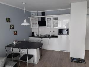 - une cuisine avec des placards blancs, une table et des chaises dans l'établissement Apartament całoroczny Bliżej Morza, à Kołobrzeg