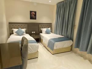 a hotel room with two beds and a table at أزد للشقق المخدومة in Tanomah