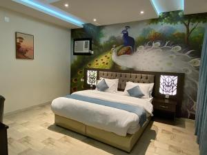 a bedroom with a large bed with a peacock painting on the wall at أزد للشقق المخدومة in Tanomah