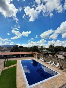 a swimming pool with a blue sky with clouds at Pousada o Amanhecer in Tiradentes