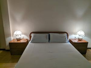 1 dormitorio con 2 mesitas de noche con 1 cama y 2 lámparas en Casa di Gio en PalaiónTsiflíkion