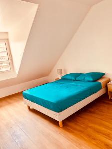 um quarto com uma cama com lençóis azuis e uma janela em LOFT T2 en couleur en plein centre ville Fort-De-France Martinique em Fort-de-France