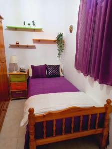 a bed in a room with purple sheets at La casa de Isabel in Mazo