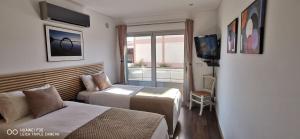 a hotel room with two beds and a television at Terraços da Baía - São Martinho do Porto in São Martinho do Porto