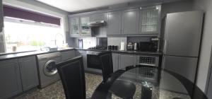 cocina con nevera y mesa de cristal en Lovely 3 Bed Home In Glasgow with FREE Parking, en Glasgow