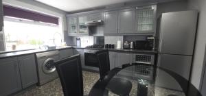 a kitchen with a refrigerator and a glass table at Lovely 3 Bed Home In Glasgow with FREE Parking in Glasgow