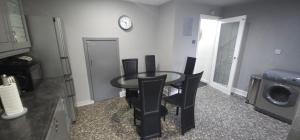 a dining room table with chairs and a clock on the wall at Lovely 3 Bed Home In Glasgow with FREE Parking in Glasgow
