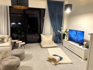 uma sala de estar com um sofá e uma televisão em Cozy Al Raha Beach Home em Abu Dhabi