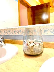 eine Glasvase gefüllt mit Sand und Muscheln auf einer Theke in der Unterkunft Praia Baluarte by Serendipia Turismo in San Pedro + 7 Fotos