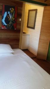 a bedroom with a white bed and a painting on the wall at Villa Rasta - Ocean View Bungalows in Port Antonio