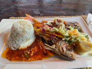 un plato de comida con arroz y carne y hortalizas en Villa Rasta - Ocean View Bungalows en Port Antonio