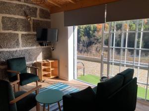 a living room with a large window and a tv at Quinta de Varzielas - Agroturismo in Castelo de Paiva