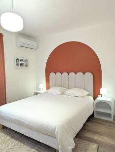 um quarto com uma grande cama branca e uma grande cabeceira de cama. em Le numéro 1 em Perpignan