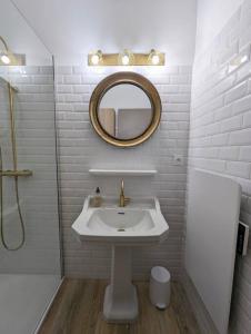 uma casa de banho branca com um lavatório e um espelho em Le numéro 1 em Perpignan