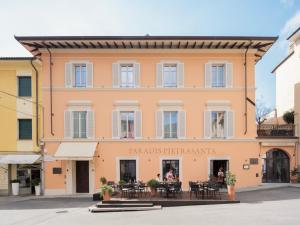 un bâtiment avec des tables et des chaises devant lui dans l'établissement Paradis Pietrasanta, à Pietrasanta