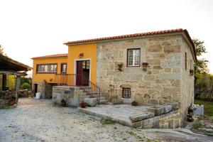 een oud stenen huis met een gele bij Casa do Ribeiro in Lago