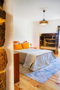 ein Schlafzimmer mit einem großen Bett mit orangefarbenen Kissen in der Unterkunft Casa do Ribeiro in Lago