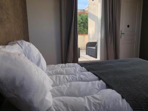 Bett mit weißer Bettwäsche in einem Zimmer mit Fenster in der Unterkunft La Villa W’ILLYS in Montpellier