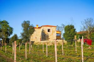 una vecchia casa in pietra in un campo con una recinzione di Casa do Ribeiro a Lago