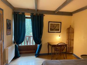 Bonneval的住宿－Auberge de la dorette，一间卧室配有桌子和蓝色窗帘的窗户