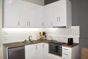 cocina con armarios blancos, fregadero y microondas en KAPA Central Apartment, en Kalamata