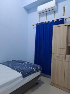 1 dormitorio con cama y cortina azul en HOMESTAY PANDAN, en Halangan