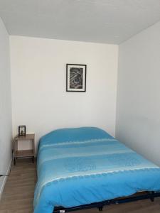 ein Schlafzimmer mit einem blauen Bett in einem weißen Zimmer in der Unterkunft Maison CALAIS centre ville L in Calais
