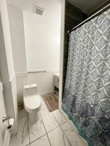 y baño con aseo y cortina de ducha. en 2bd Spacious S. Philly Row-House, Wi-Fi & 1.5 bath, en Filadelfia
