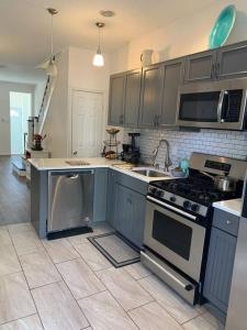 a kitchen with gray cabinets and a stove and sink at 2bd Spacious S. Philly Row-House, Wi-Fi & 1.5 bath in Philadelphia