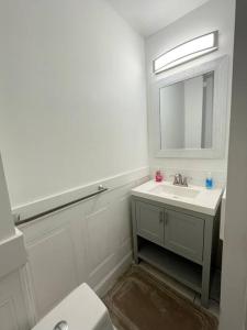 Baño blanco con lavabo y espejo en 2bd Spacious S. Philly Row-House, Wi-Fi & 1.5 bath, en Filadelfia