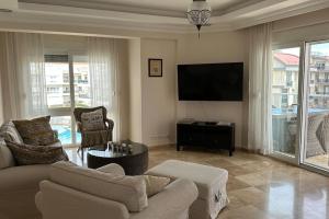 sala de estar con sofá y TV de pantalla plana en Odyssey Park Penthouse, en Belek