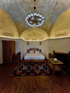 Un dormitorio con una cama grande y una lámpara de araña. en Marhaba boutique Madrasah 15th-16th century, en Bukhara