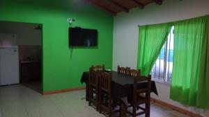 ポトレロ・デ・ロス・フネスにあるCabañas El Doralの緑の壁のダイニングルーム(テーブル、椅子付)
