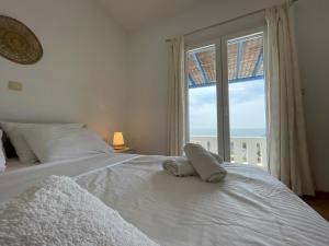 a bedroom with a white bed with a large window at Villa Maniati Studios in Agios Petros