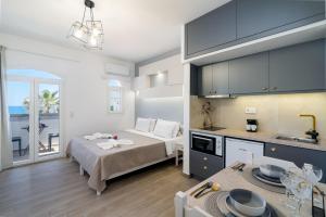 a bedroom with a bed and a kitchen with a table at Renata Mare Beachside Studios in Hersonissos