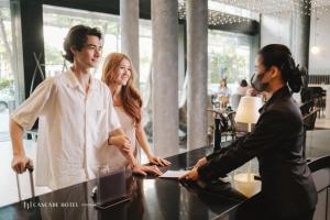 Cascade Hotel Bangkok في بانكوك: مجموعة من ثلاثة أشخاص واقفين حول طاولة