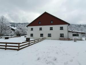 un gran edificio blanco con techo rojo en la nieve en appart l'Écureuil 4 étoiles en Cornimont